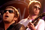 Liam e Noel Gallagher durante show do Oasis nos anos 2000 - Foto: Paul Bergen / Redferns